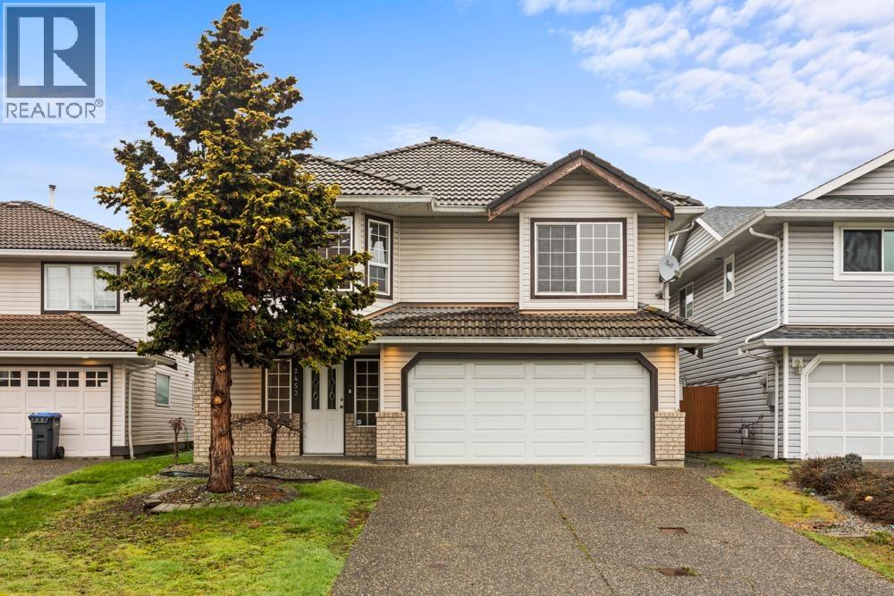 A house with a tree in front and a REALTOR sign in the corner.