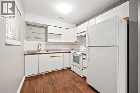 A white kitchen with wood floors and white appliances.