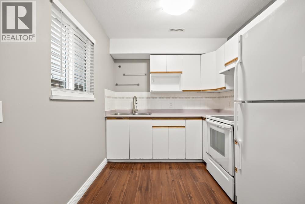 A kitchen with white appliances and wooden floors.