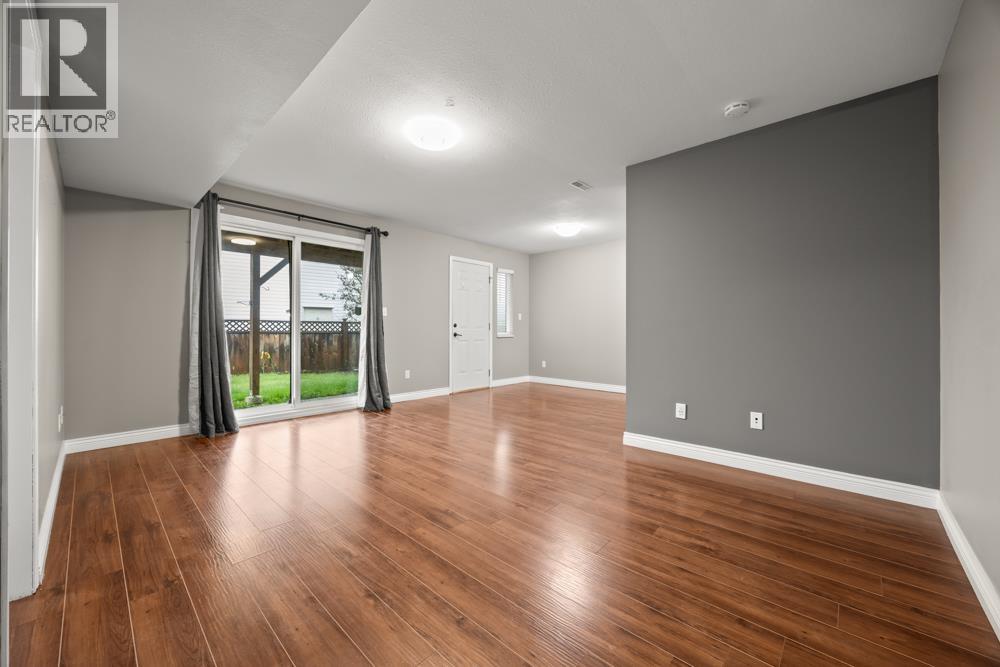 A spacious room with wooden flooring and a sliding glass door.