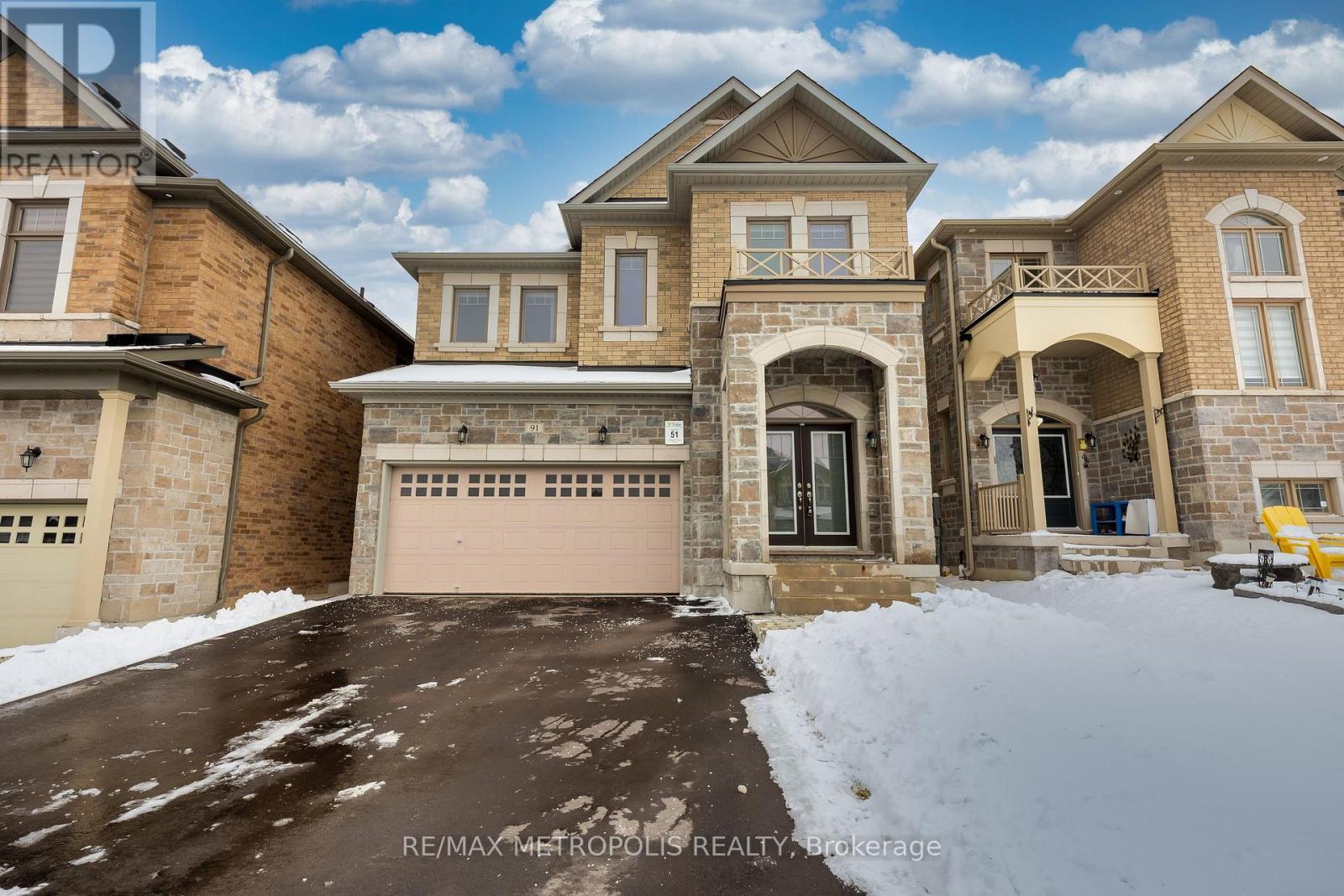 A large, luxurious house with a snow-covered driveway in front.