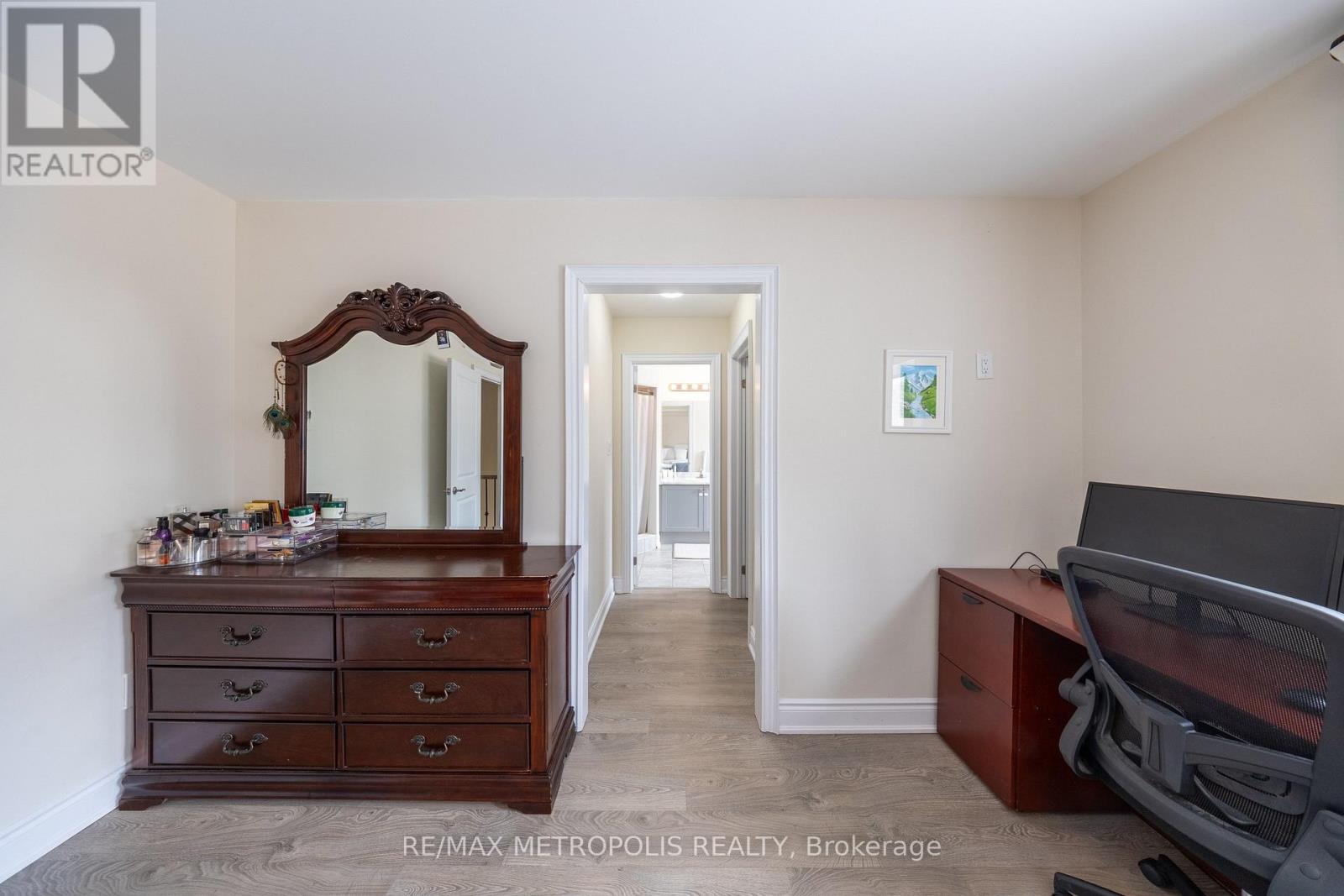 A bedroom with a brown dresser and a mirror.