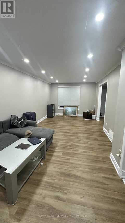 A living room with a grey couch and a wooden floor.