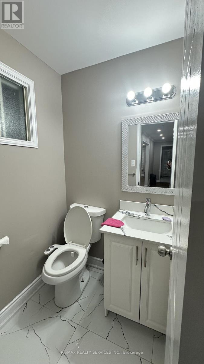 A bathroom with a toilet, sink, and mirror.