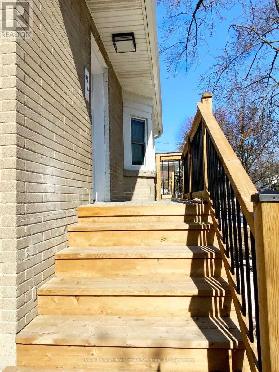 A set of wooden stairs with a black railing.