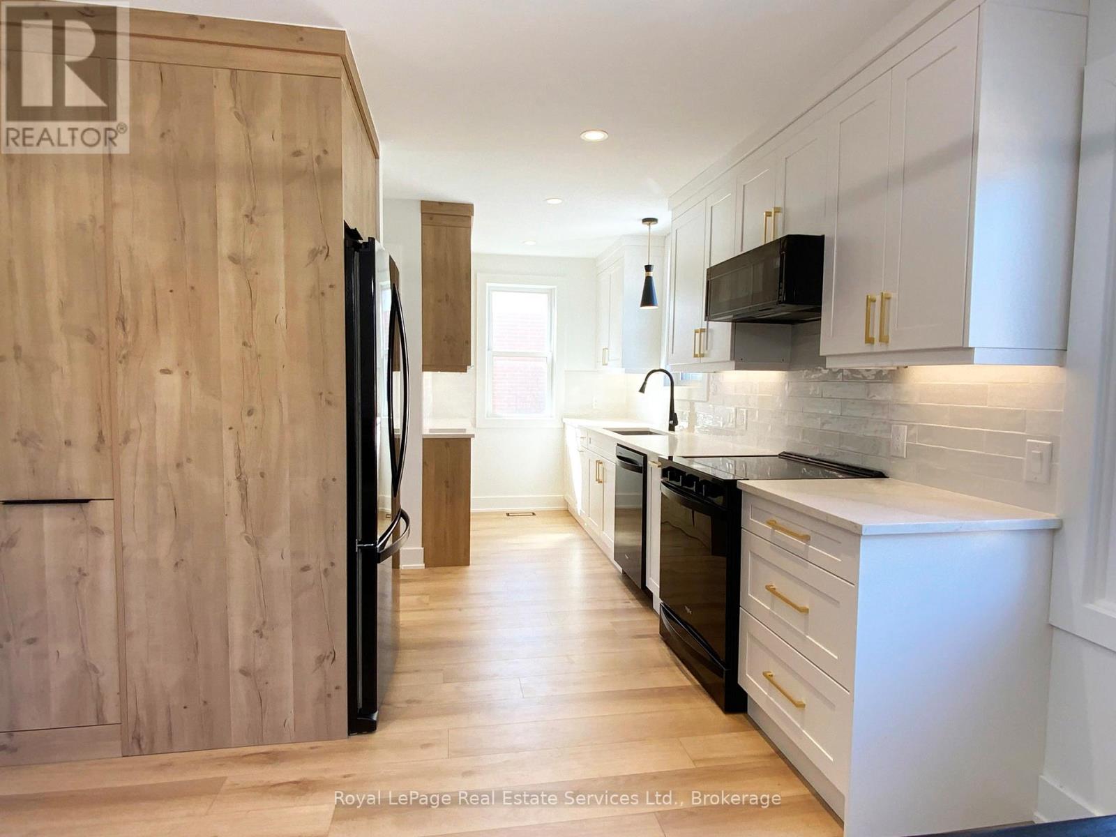 A modern kitchen with wooden cabinets and black appliances.