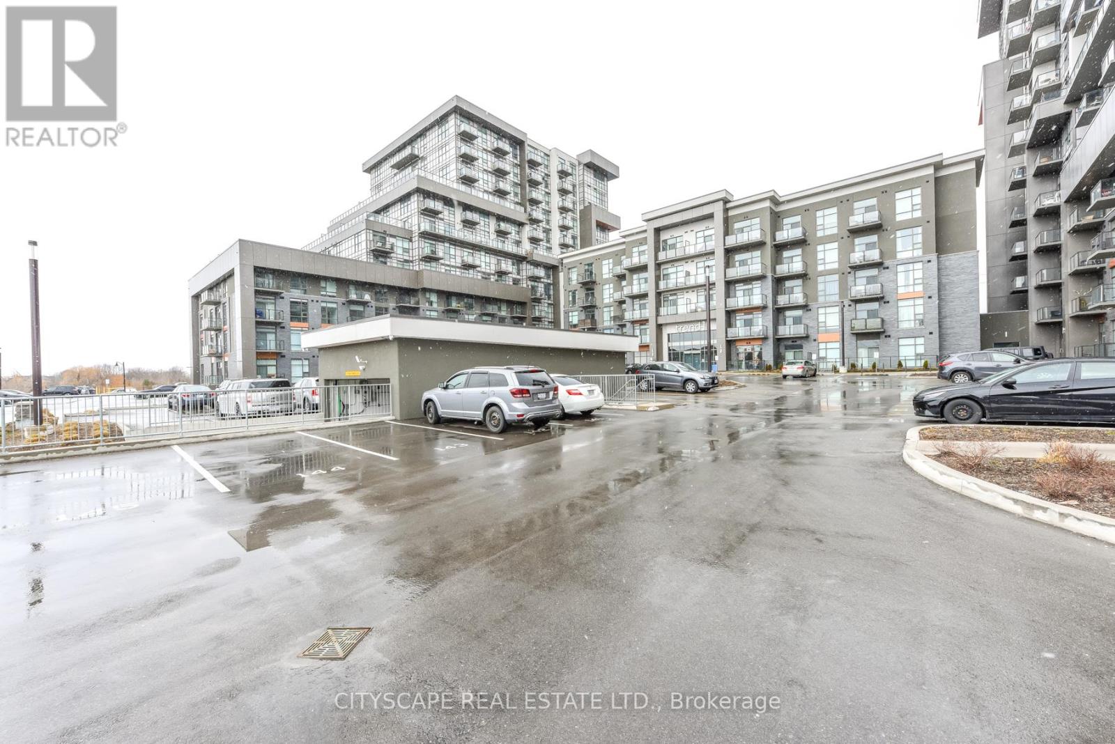 A wet parking lot with cars and apartment buildings in the background.