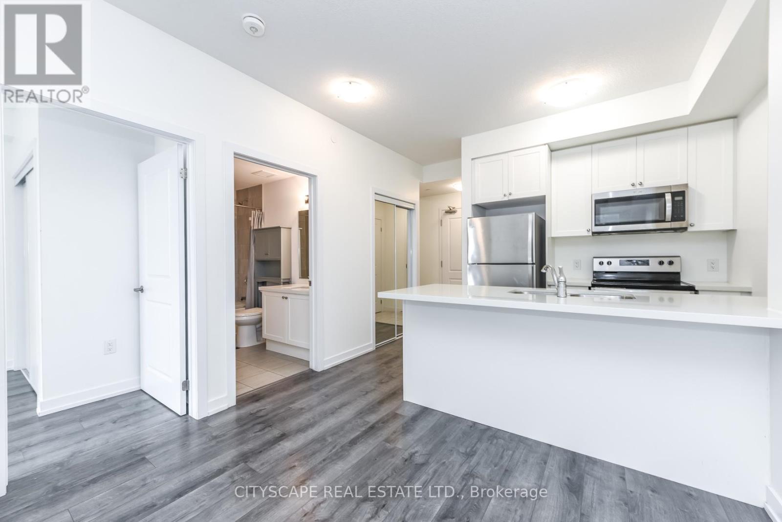 A kitchen with white cabinets and a stainless steel refrigerator.