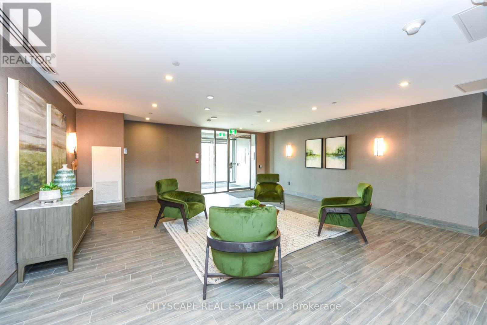 A spacious room with green chairs and a wooden floor.