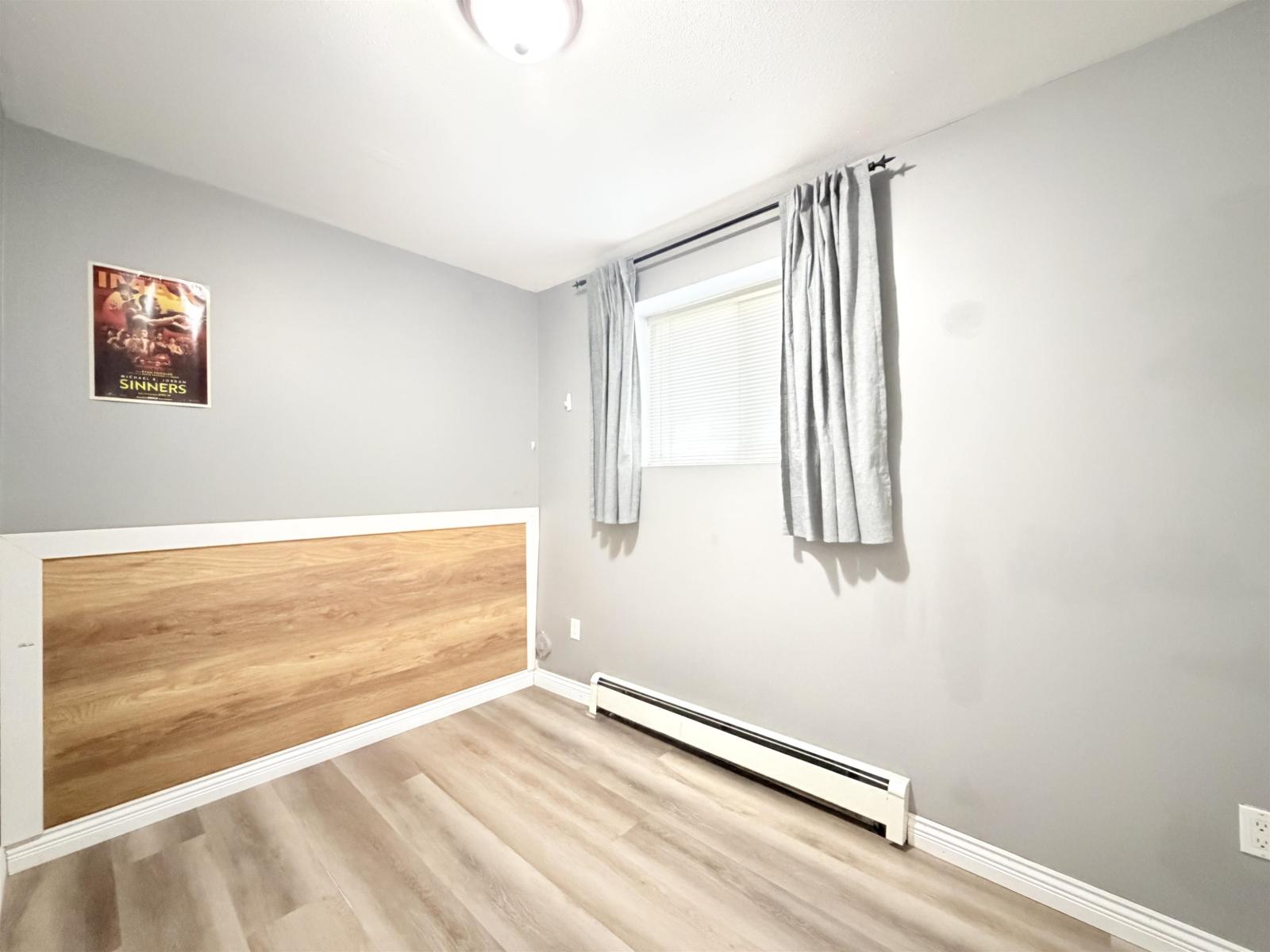 A room with a window and a wooden headboard.