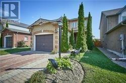 A house with a driveway and a tree in front.