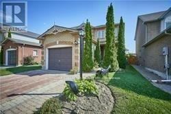 A house with a driveway and a tree in front.