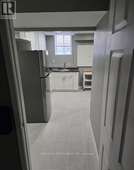 A kitchen with white cabinets and a black refrigerator.