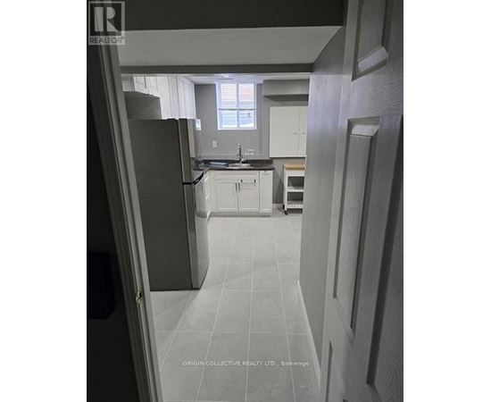 A kitchen with white cabinets and a black refrigerator.
