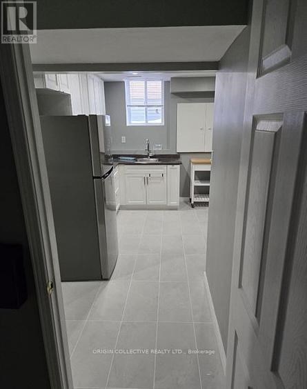 A kitchen with white cabinets and a black refrigerator.