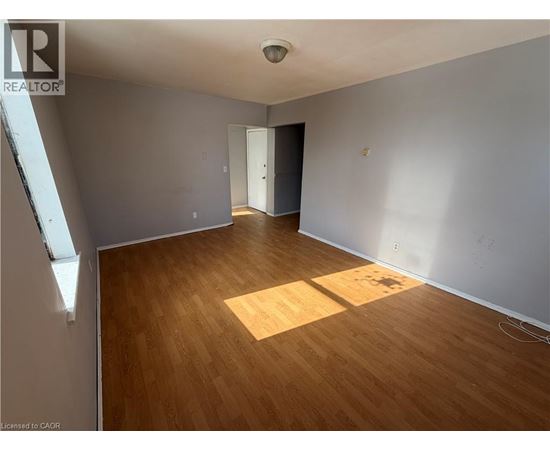 A room with wooden flooring and a door on the right side.