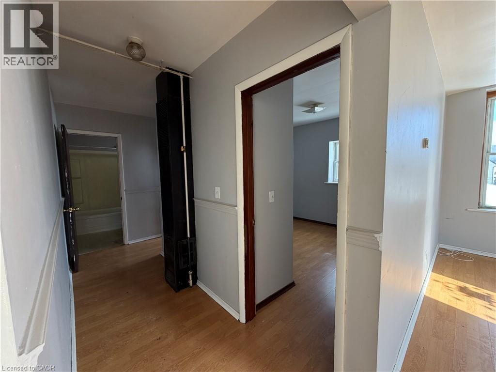 A room with a wooden floor and white walls, with a door open to another room.