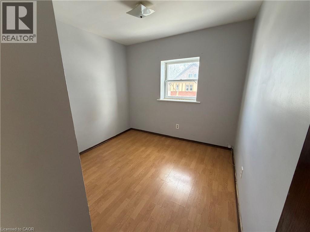 A room with wooden flooring and a window showing a building outside.