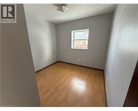 A room with wooden flooring and a window showing a building outside.