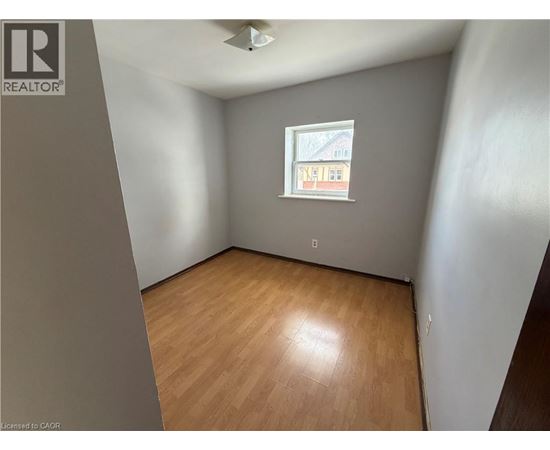 A room with wooden flooring and a window showing a building outside.