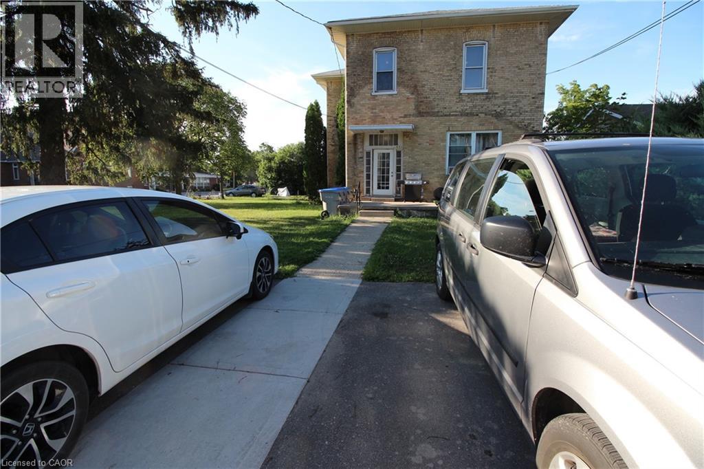 Two cars are parked on a driveway in front of a house.