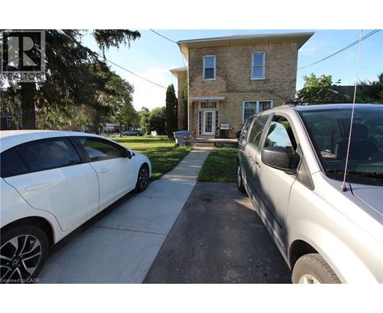 Two cars are parked on a driveway in front of a house.