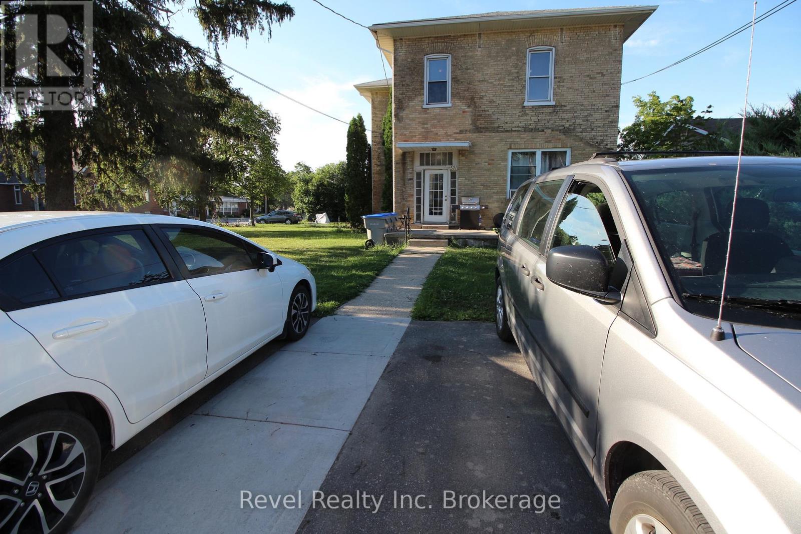 Two cars parked in front of a house with the text "Revel Realty Inc. Brokerage" on the image.