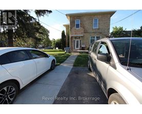 Two cars parked in front of a house with the text "Revel Realty Inc. Brokerage" on the image.