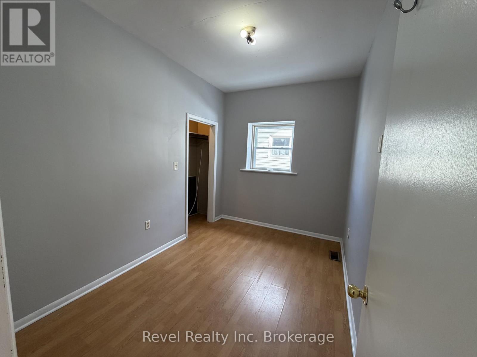 A room with a door and a window with Revel Realty Inc. Brokerage written on the wall.
