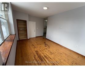 A room with wooden floors and white walls, with a window on the left side.