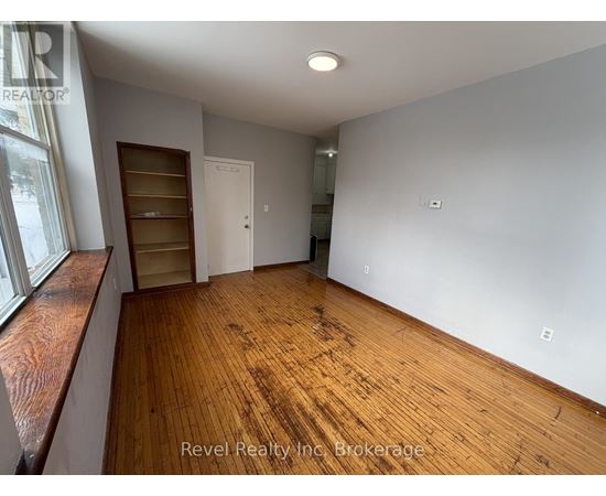 A room with wooden floors and white walls, with a window on the left side.