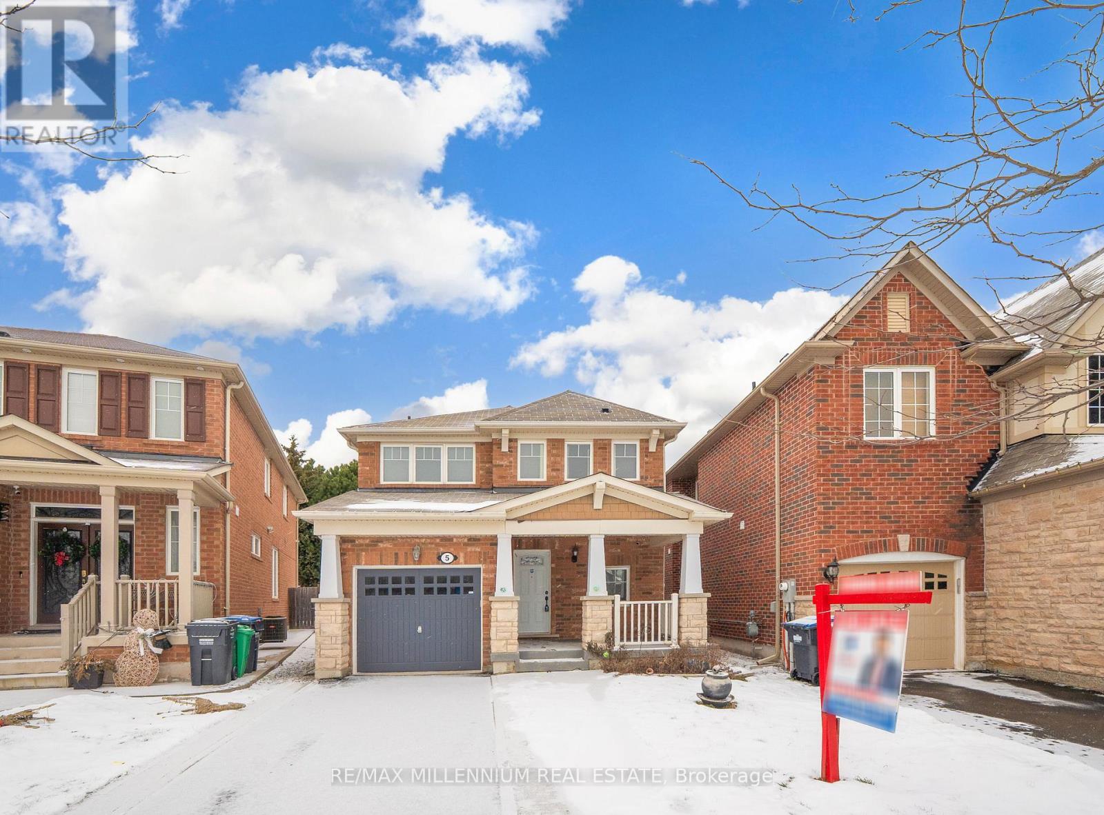 A real estate sign is in front of a house with a garage.