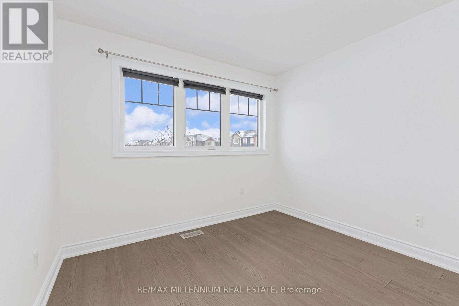 A room with a window showing a view of the sky and buildings outside.