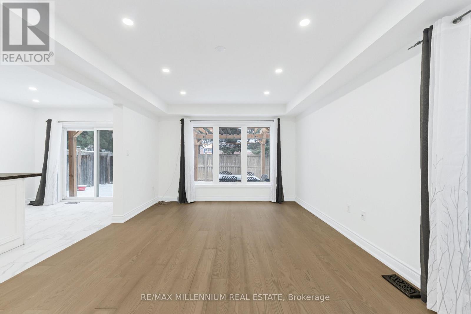 A spacious room with wooden flooring and white walls.