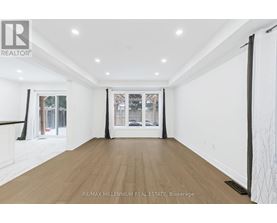 A spacious room with wooden flooring and white walls.