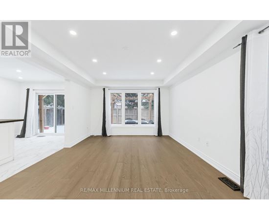 A spacious room with wooden flooring and white walls.