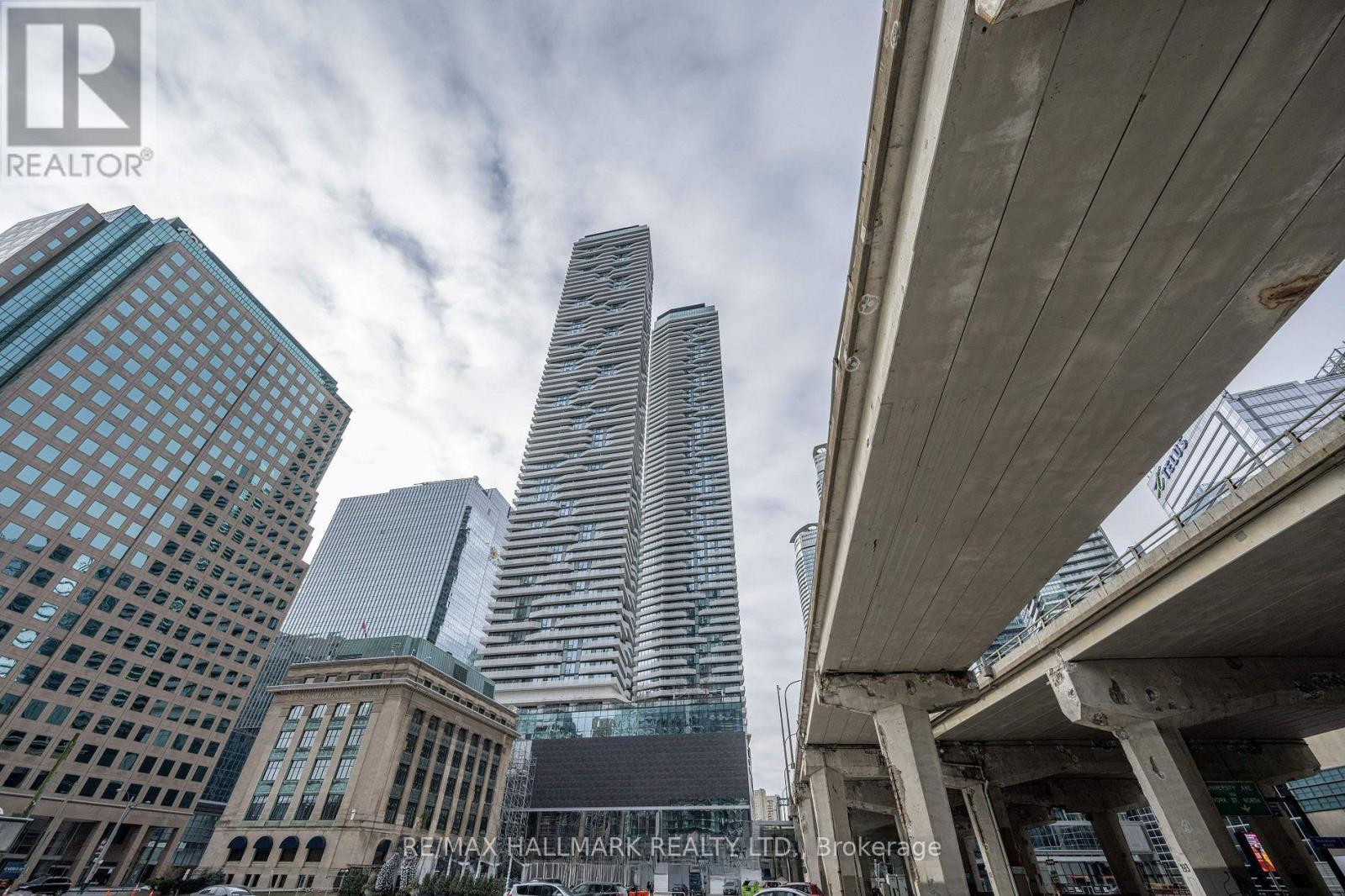 A cityscape with tall buildings and a bridge overhead.