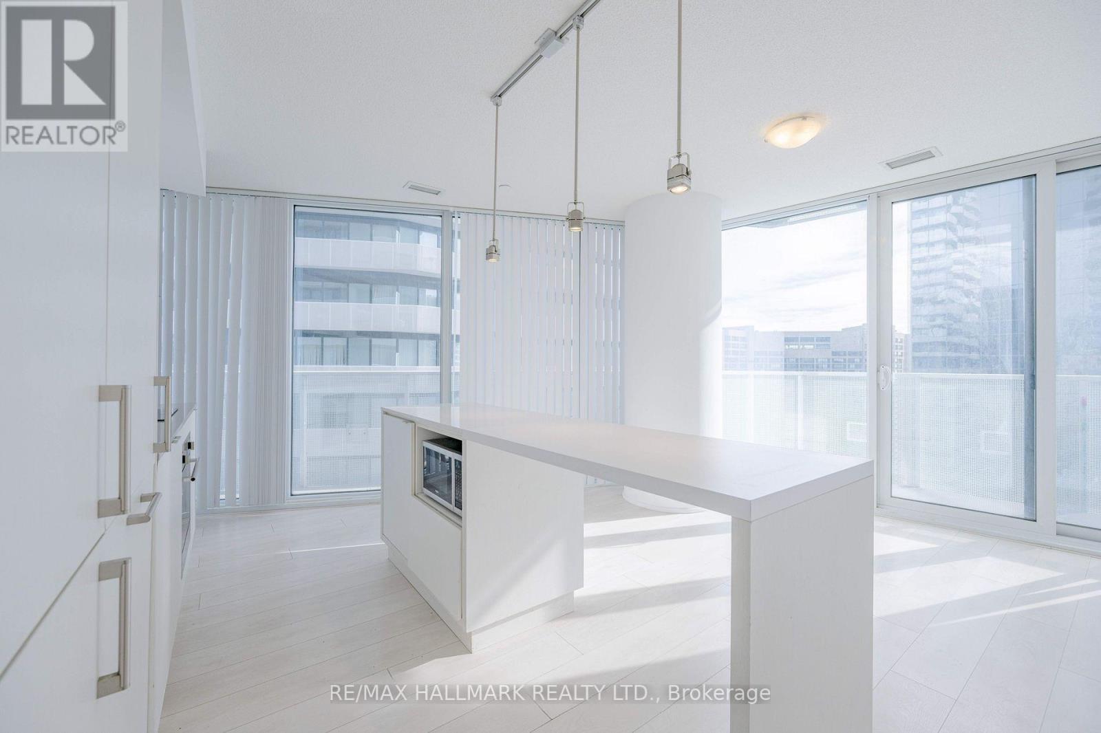 A modern white kitchen with a large island in the middle.