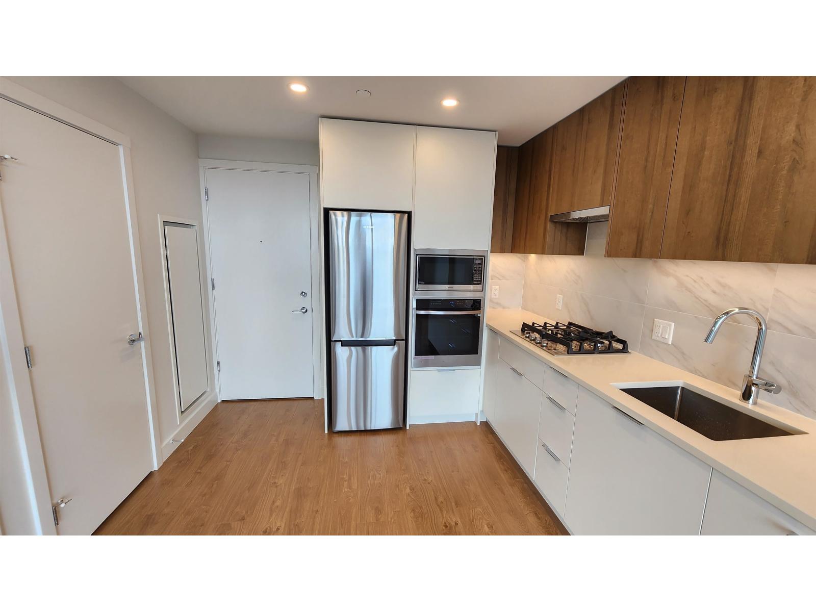 A kitchen with a stainless steel refrigerator, oven, and sink.