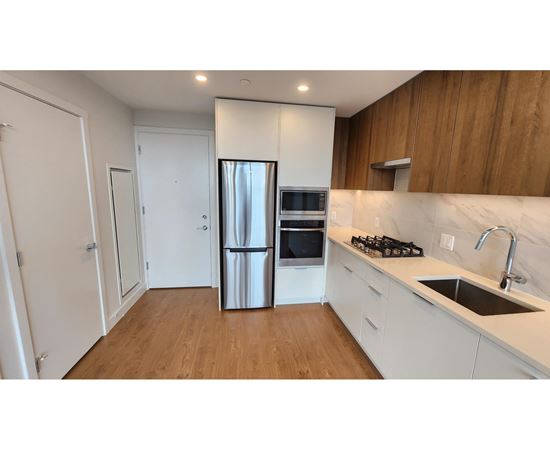 A kitchen with a stainless steel refrigerator, oven, and sink.
