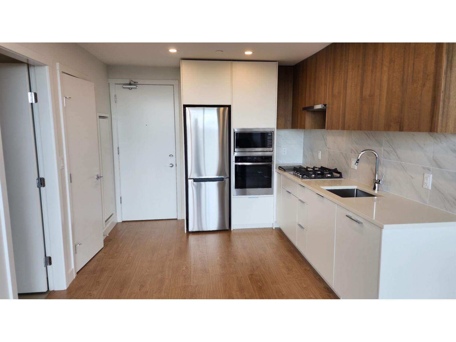 A kitchen with a refrigerator, sink, and cabinets.