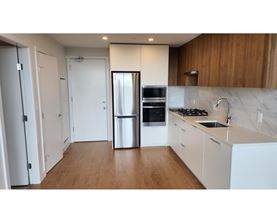 A kitchen with a refrigerator, sink, and cabinets.