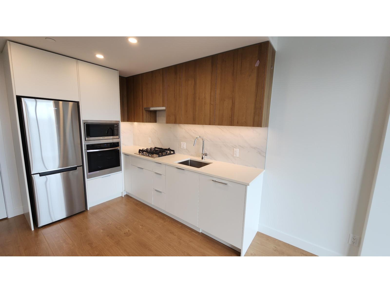 A modern kitchen with white cabinets and a stainless steel refrigerator.