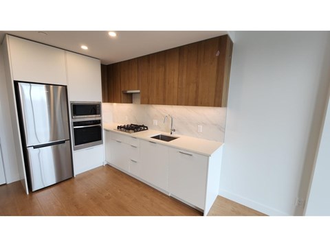 A modern kitchen with white cabinets and a stainless steel refrigerator.