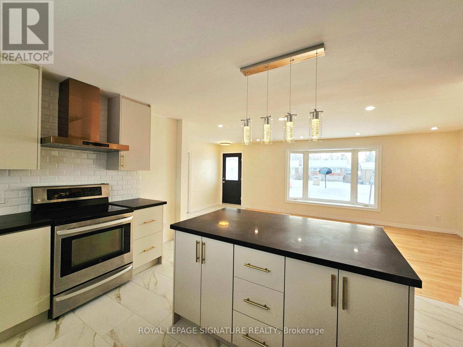 A modern kitchen with a black countertop and stainless steel appliances.