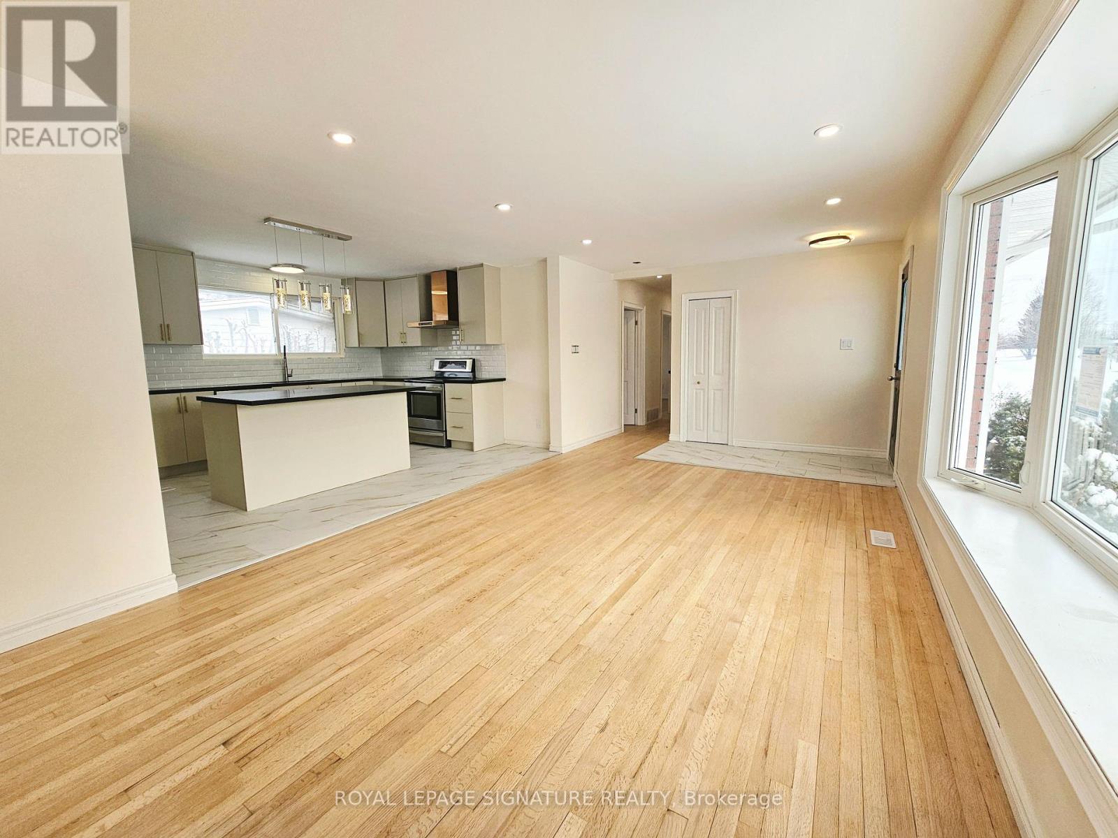 A spacious room with wooden flooring and white walls.