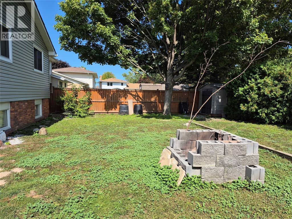 A backyard with a cinder block wall and a tree.