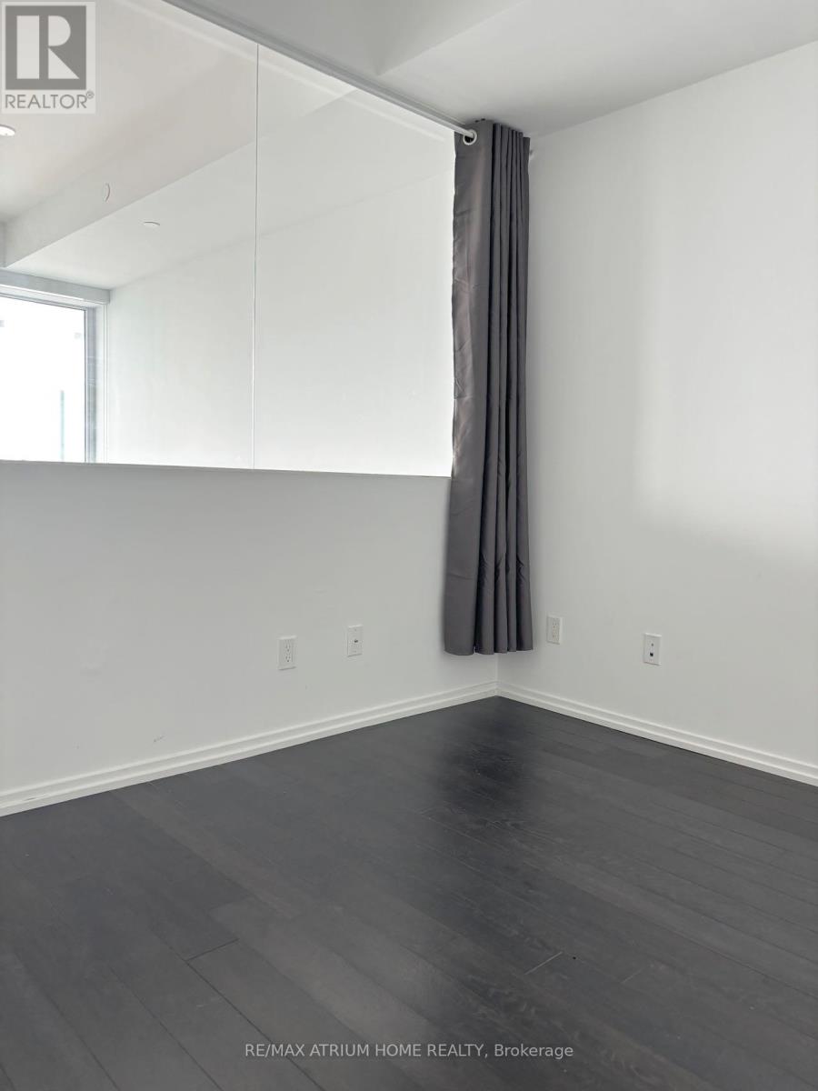 A room with a grey curtain and wooden floor.