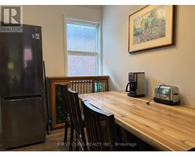 A kitchen with a wooden table and chairs, a refrigerator, and a window.