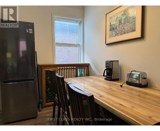 A kitchen with a wooden table and chairs, a refrigerator, and a window.